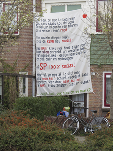 906881 Afbeelding van een groot spandoek met een gedicht van de Socialistische Partij (SP), opgehangen tegen de gevel ...